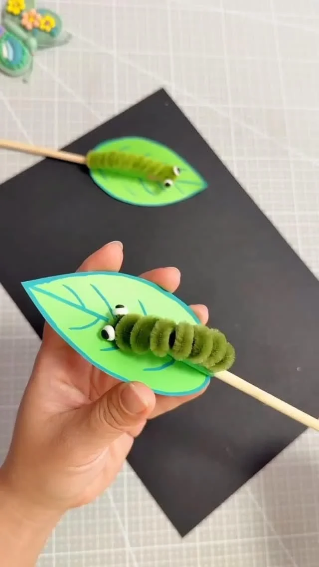Papierkunst-Dekoration einer wackeligen Raupe aus Papier und Stock für Basteleien.